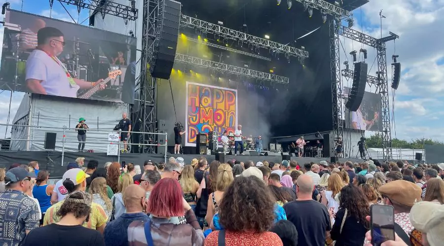 A crowd enjoys live music outdoors at Forwards Festival in Bristol. On stage features large stage featuring vibrant lighting and a colourful backdrop.