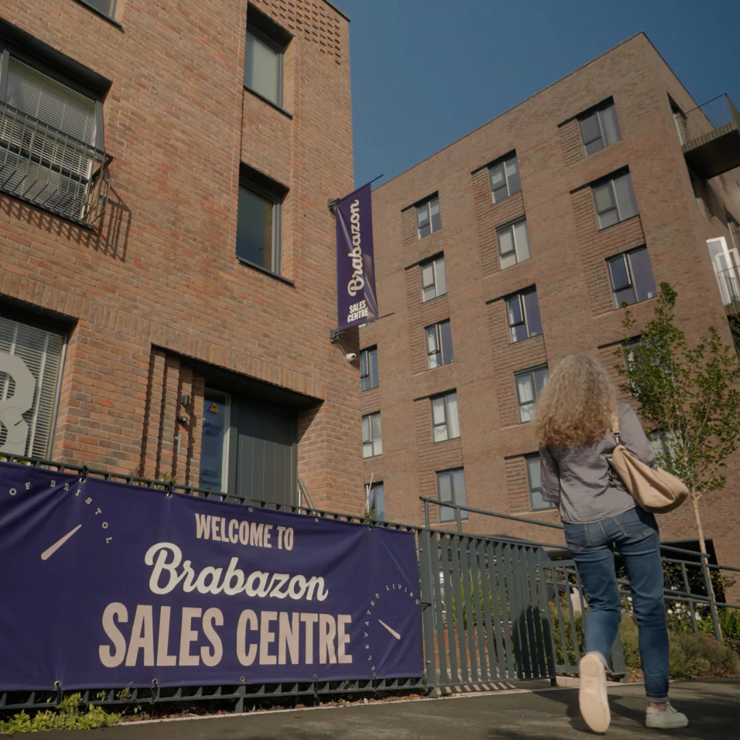 Woman walking past the Sales Centre at Brabazon, a modern brick terrace property in Bristol. 