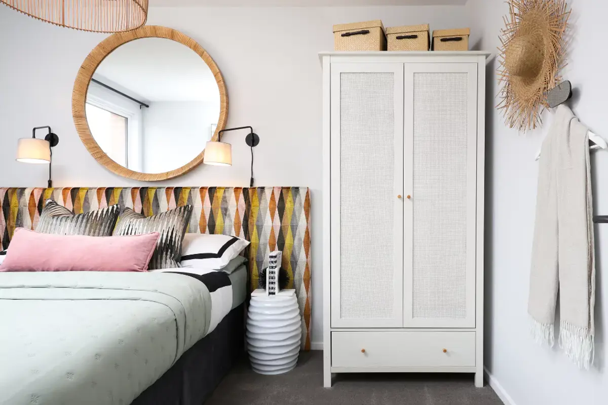 A glimpse into the double guest bedroom featuring a funky headboard, a rattan white wardrobe and stylish extras.