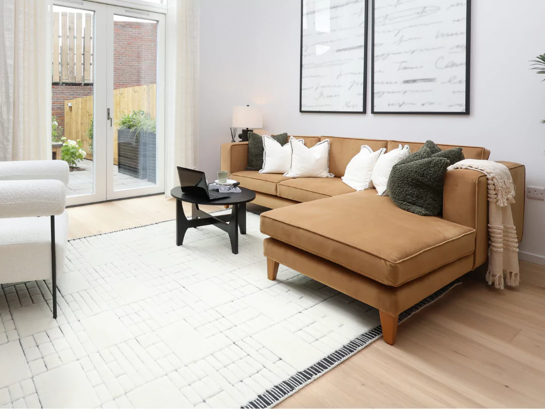 This living room is flooded with natural light featuring a beige corner sofa and cosy furnishings.
