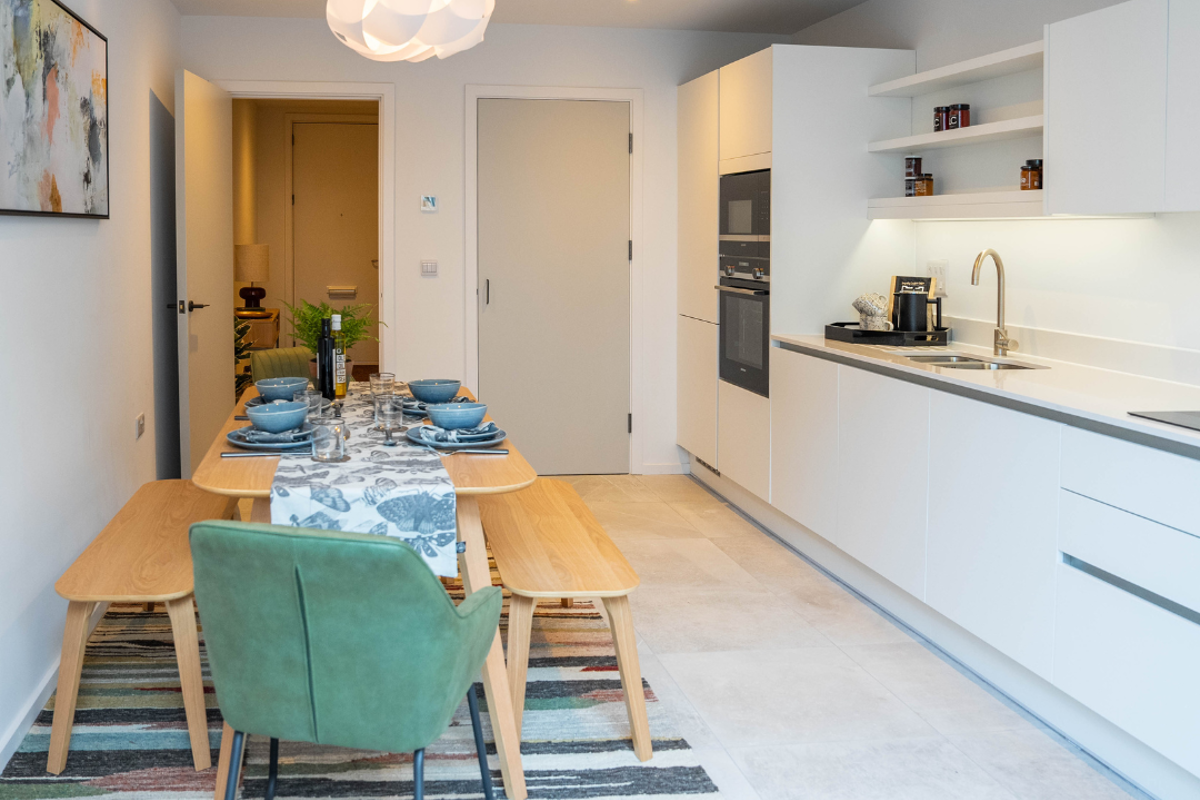 Bright kitchen-diner with modern white kitchen down one wall and a dining table.